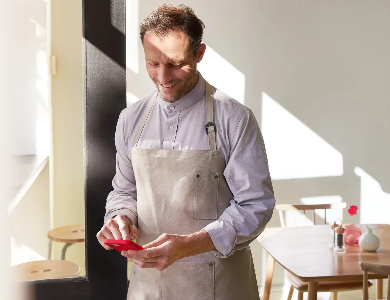Homme avec tablier de cuisine utilisant son téléphone 