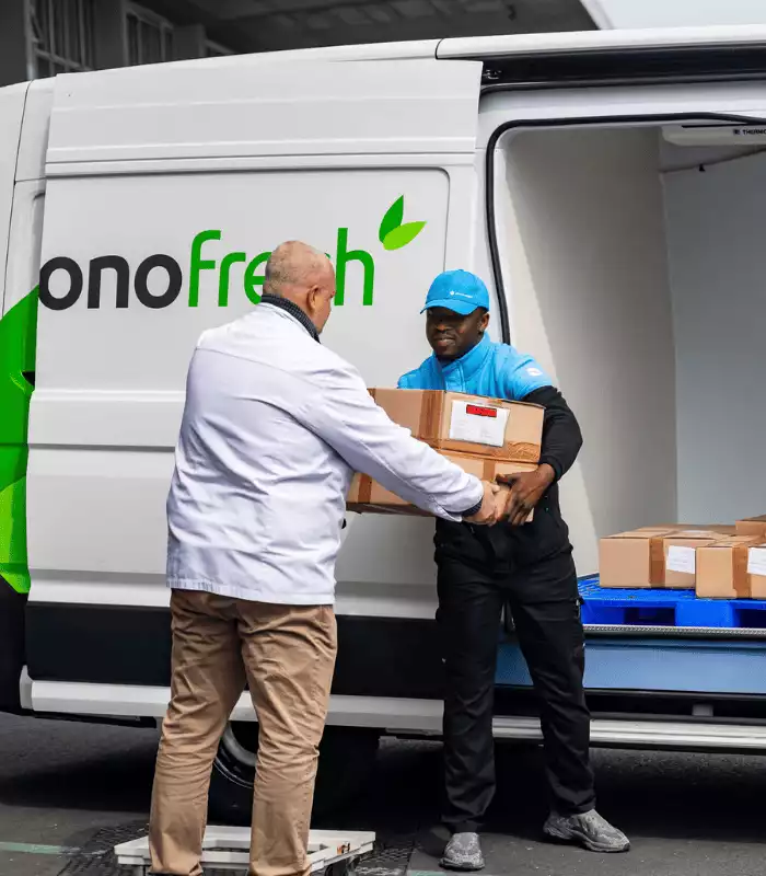 Professionnel alimentaire qui remet un colis alimentaire à un chauffeur 