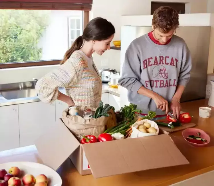Couple préparant un plat avec box alimentaire